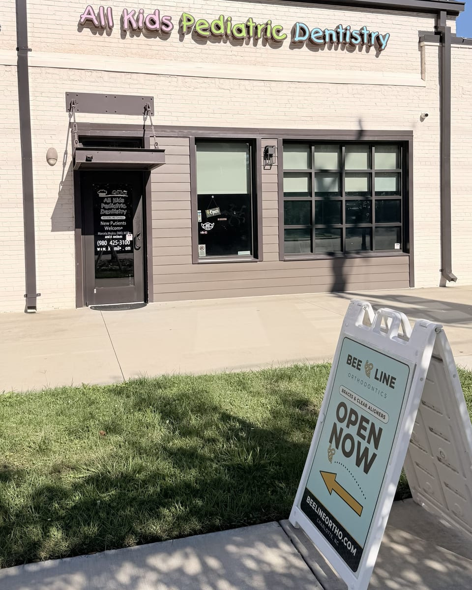The front of the building on The Plaza: the Suite 4 door, currently the All Kids Pediatric Dentistry entrance, with the Beeline Orthodontics sign on the sidewalk pointing to it